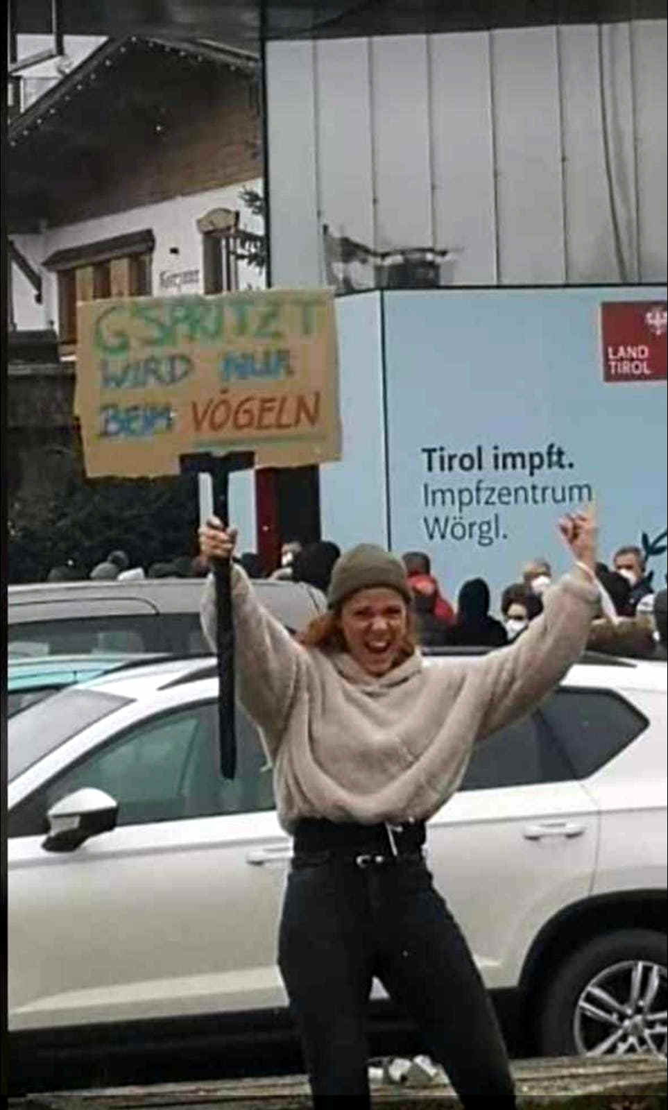 Frau hält ein Plakat vor dem Impfzentrum: „Gspritzt wird nur beim Vögeln“